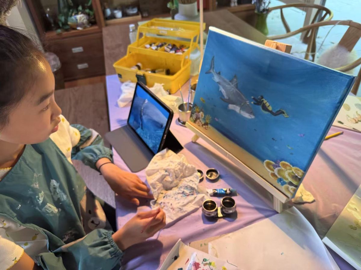 Shanni painting the shark and diver on canvas